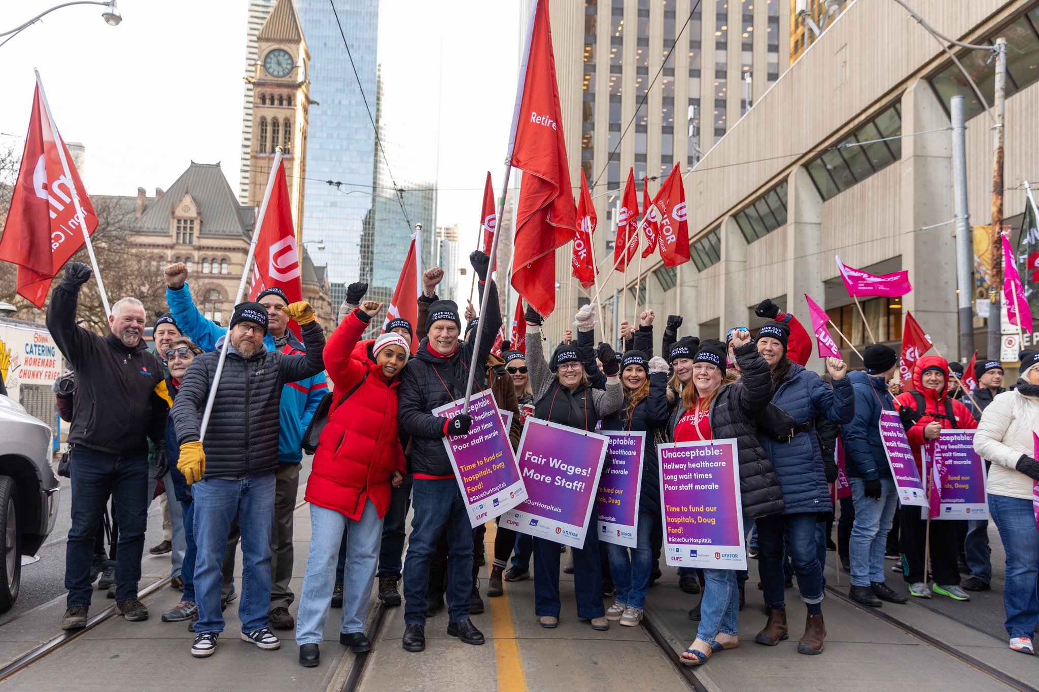 A large rally group holding Unifor flags